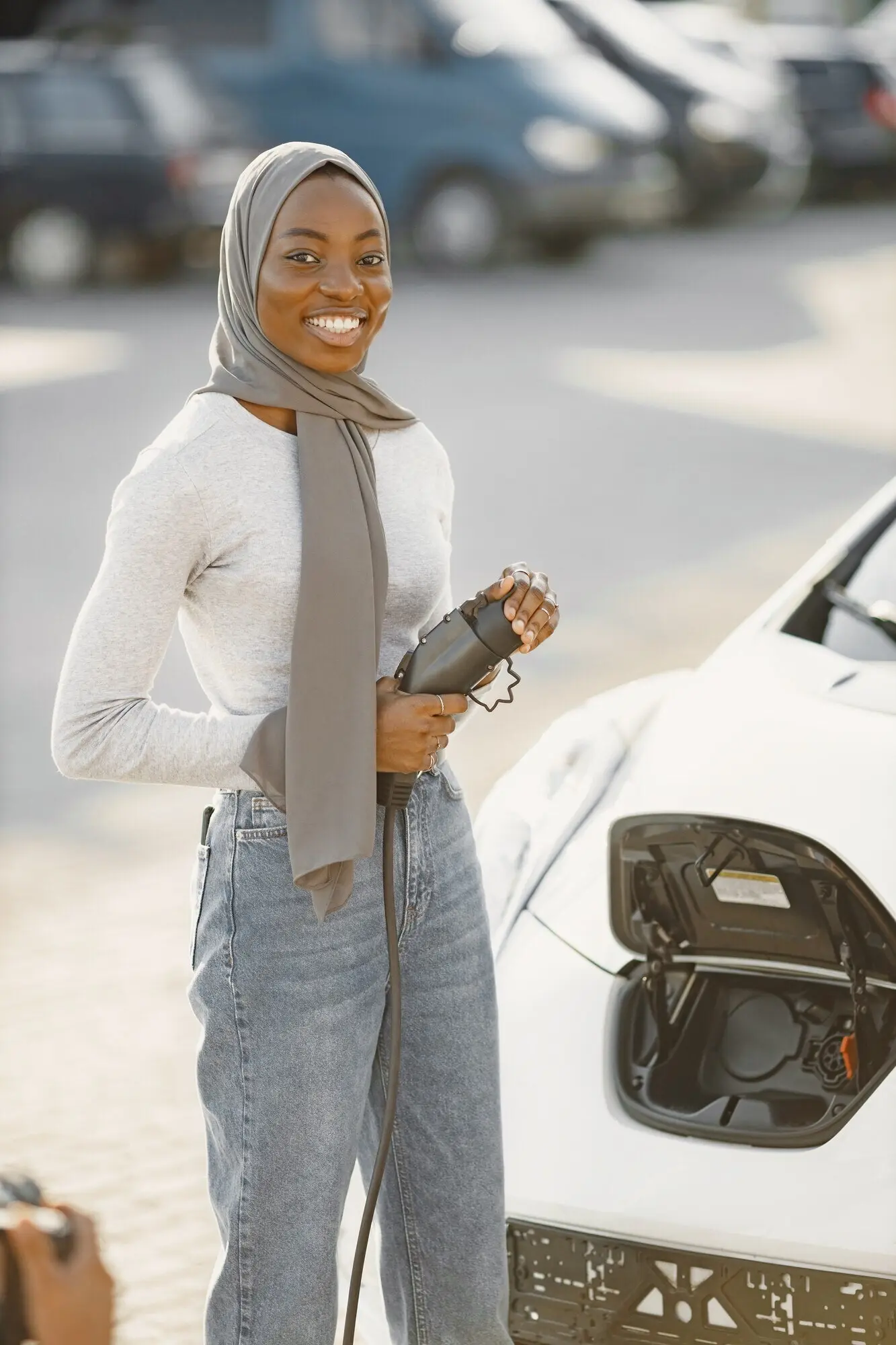 African American girl charging an electric car at a charging station.