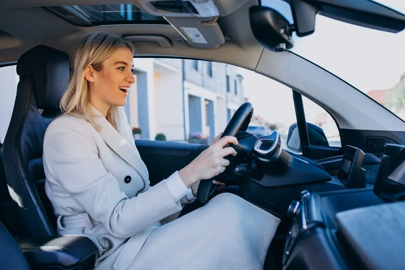 A woman sitting inside an electric car as it charges.